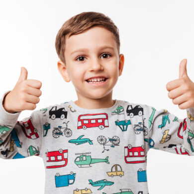 Portrait of a smiling little kid standing and showing thumbs up with two hands isolated over white background